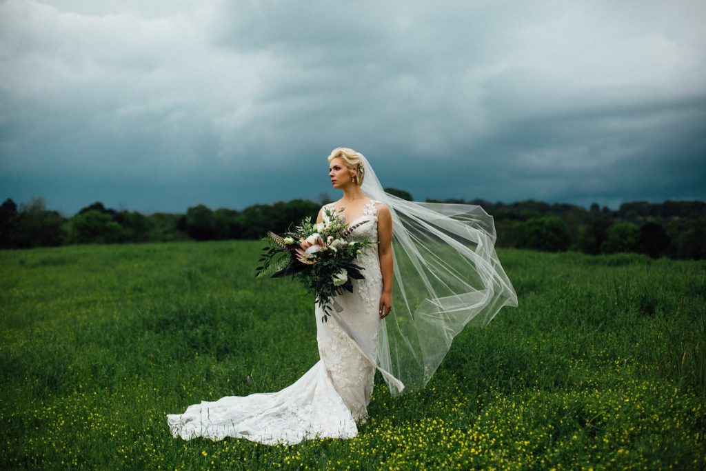 boho bride standing in a storm on a grassy hill in Tennessee