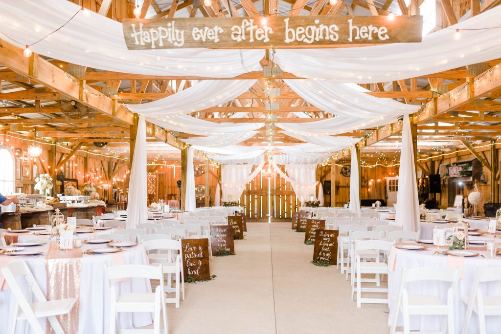 interior of barn for inside wedding ceremony with vintage wooden sign saying Happily ever after starts here.